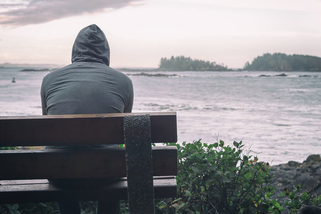 Man sitting on a bench struggling with mental illness and addiction