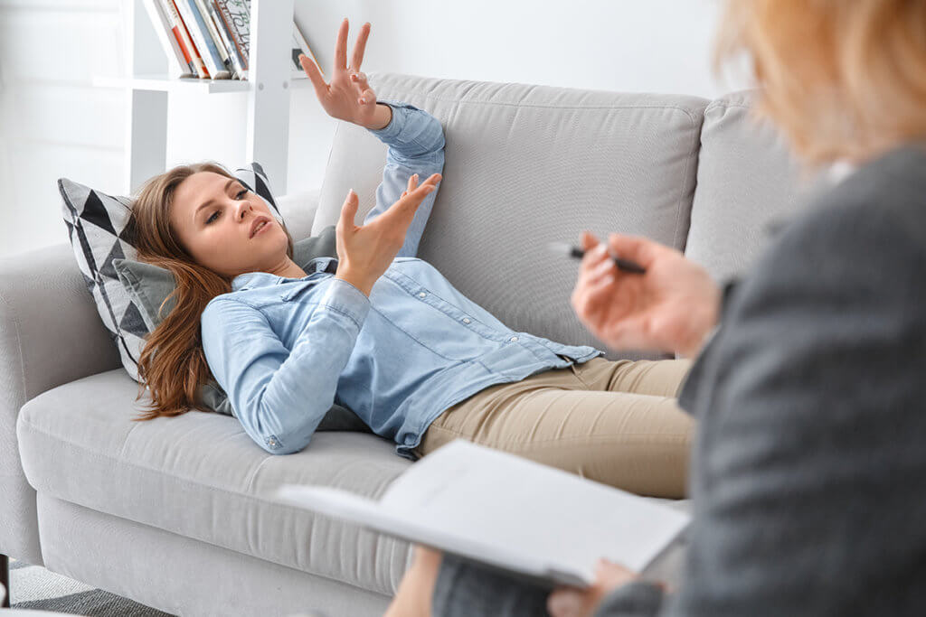 woman lies on couch and talks to female therapist about expressive therapies