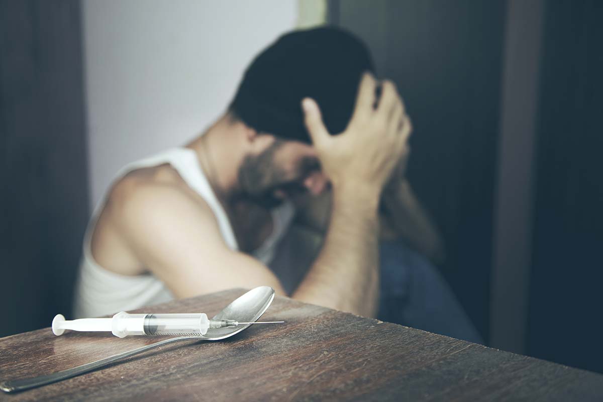 guy sitting down struggling with heroin side effects with