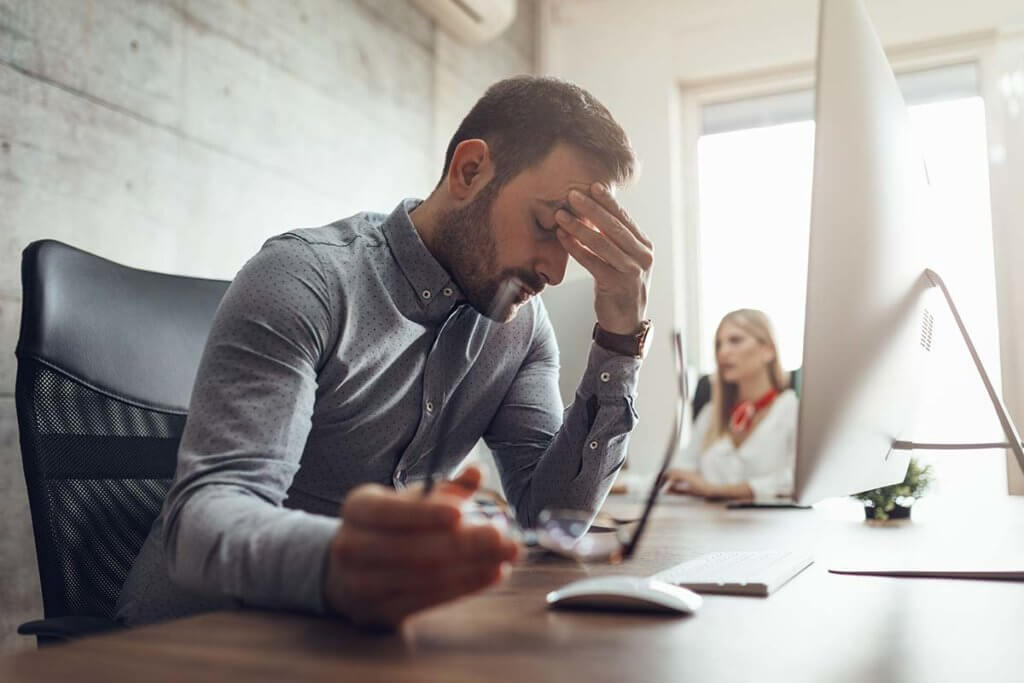 man stressed sitting at his desk trying to use stress management techniques