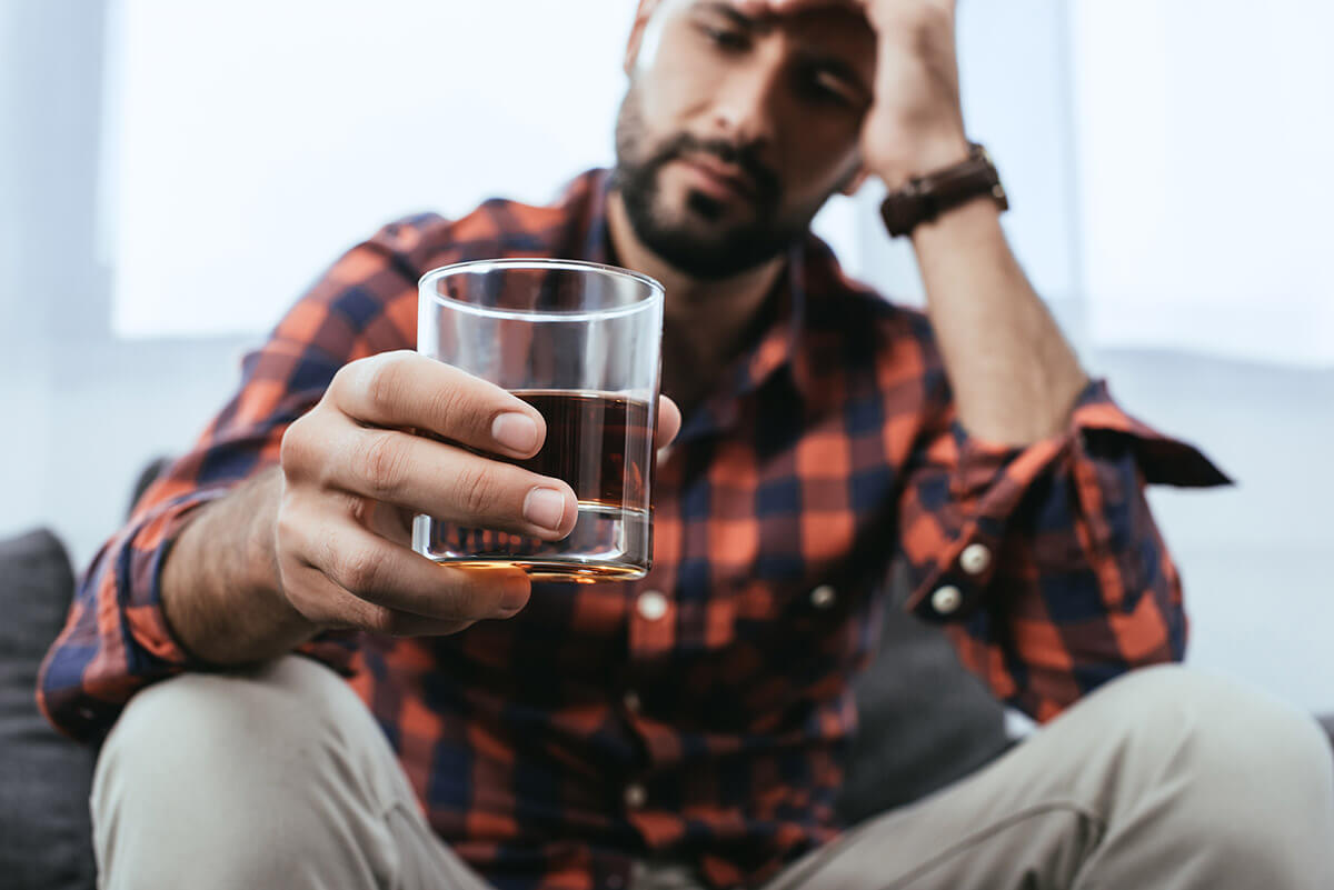 a man having a glass of whiskey in the morning realizing he has problems drinking