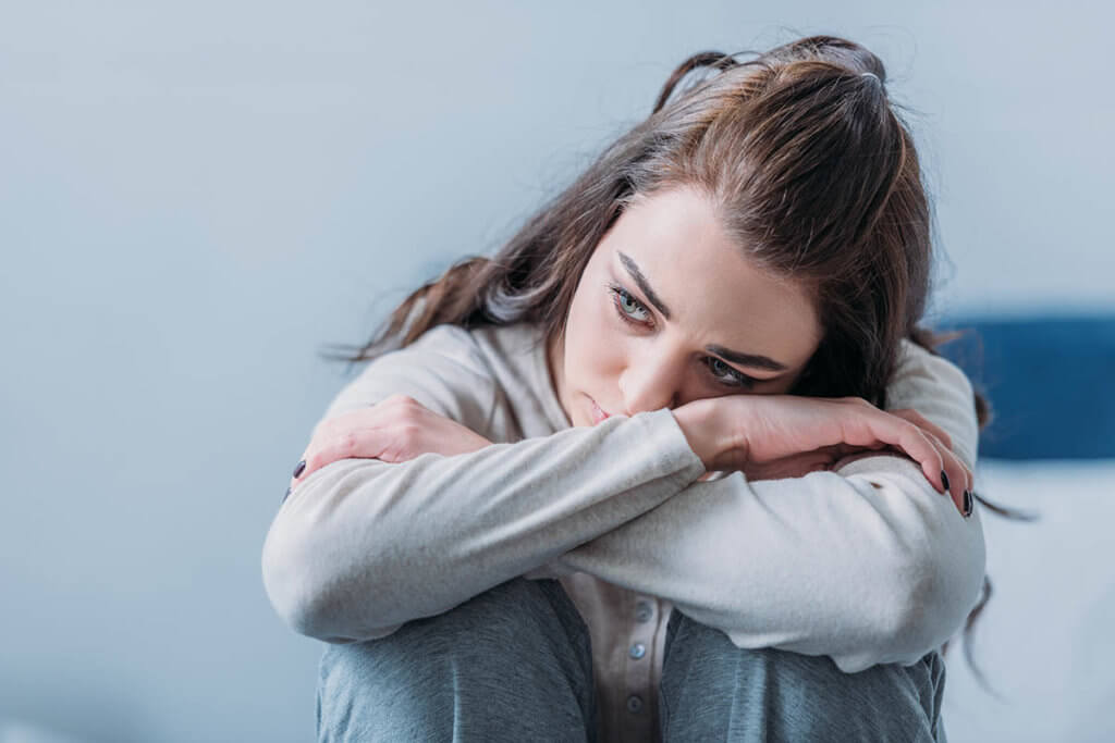 girl sitting down with her arms crossed showing signs of anxiety