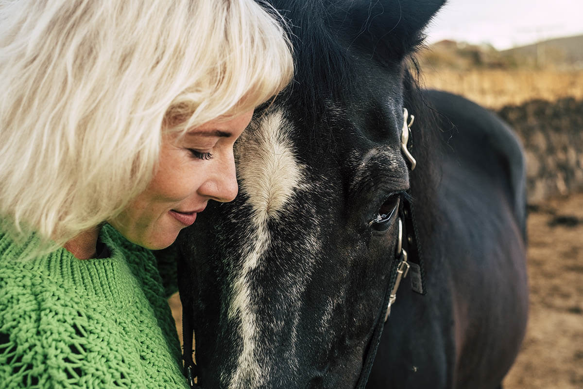 woman nuzzling horse showing benefits of equine therapy