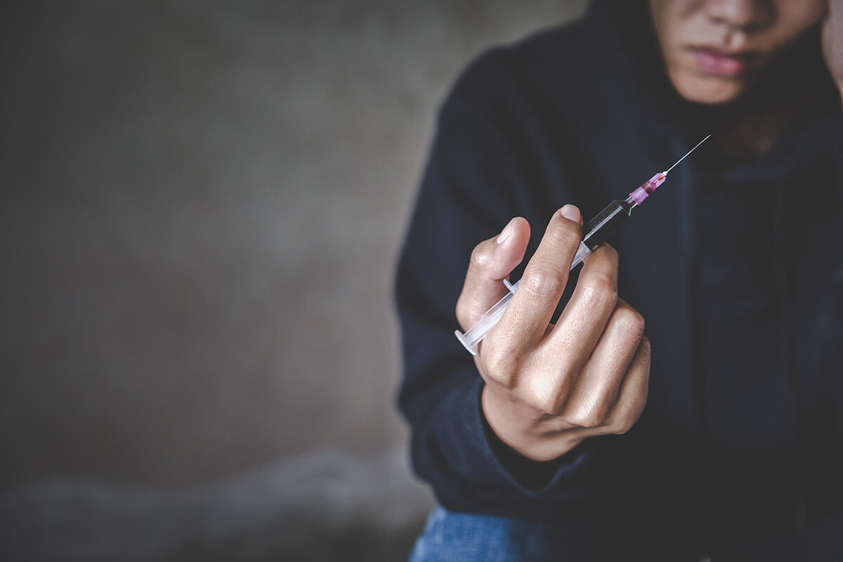 person holding a needle Signs of Heroin Addiction